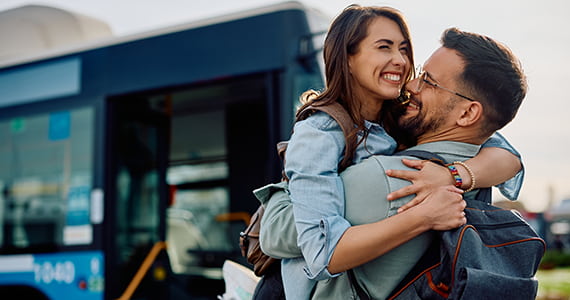 passengers happily embrace after disembarking a bus